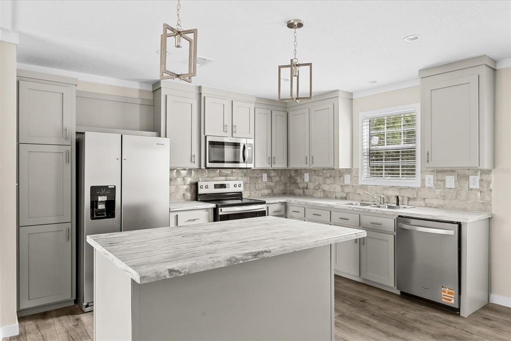 A kitchen with gray cabinets, stainless steel appliances, and a stone-look island countertop — 16226 NW 254TH STREET, OKEECHOBEE, FL