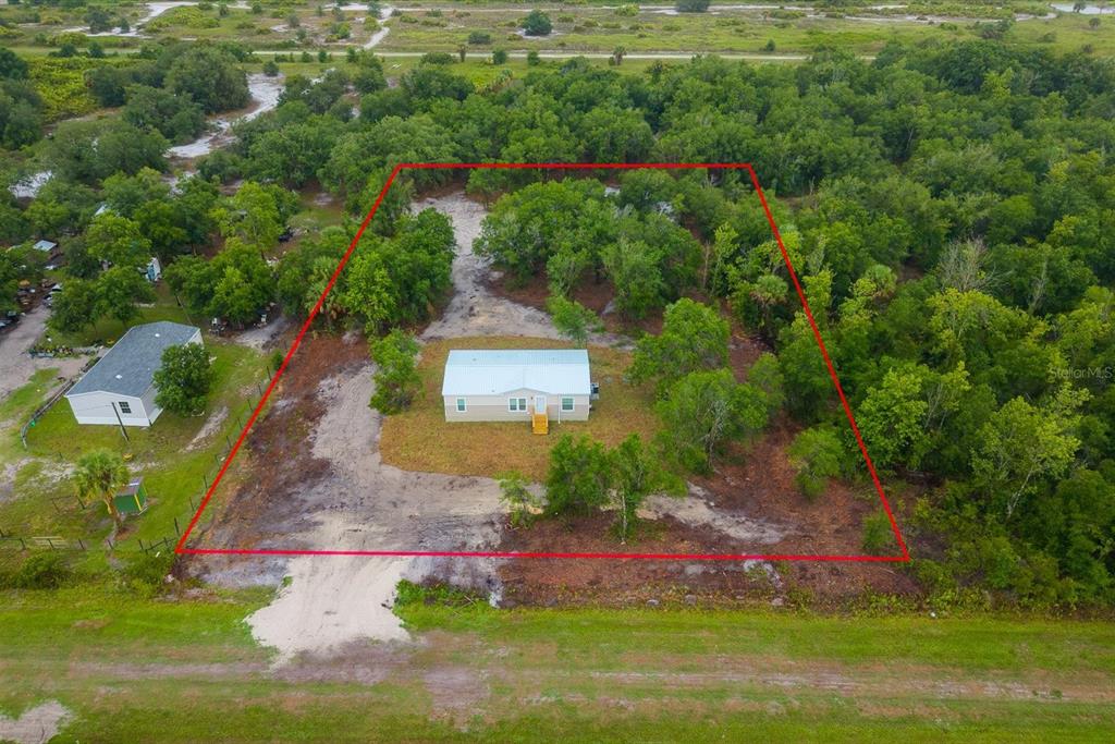 An aerial view shows a single-story house situated on a large, partially wooded lot — 16226 NW 254TH STREET, OKEECHOBEE, FL