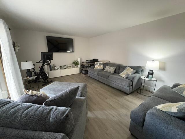 A living room features gray sofas, light wood-look flooring, and a wall-mounted television — 303 Arabian Road, Palm Springs FL 33461, PALM SPRINGS, FL