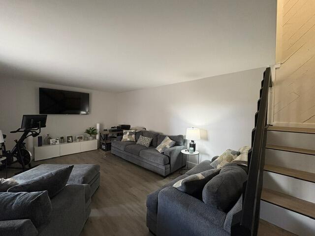 A living room features gray sofas, a wall-mounted television, and a staircase with dark railings — 303 Arabian Road, Palm Springs FL 33461, PALM SPRINGS, FL