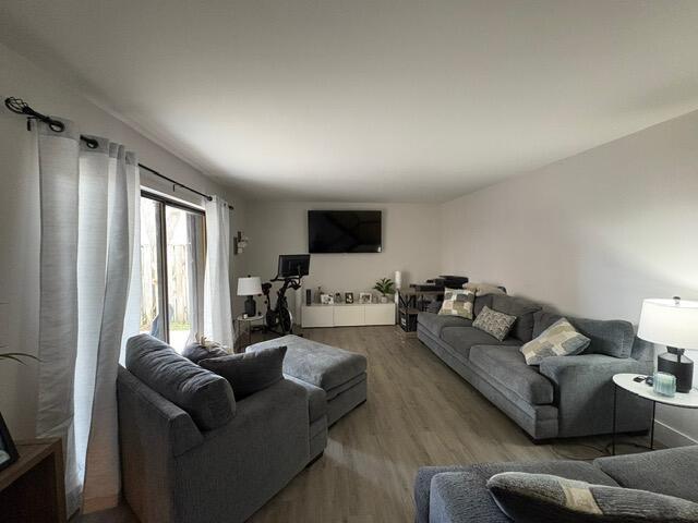 A living room features gray furniture, a wall-mounted television, and light wood-look flooring — 303 Arabian Road, Palm Springs FL 33461, PALM SPRINGS, FL