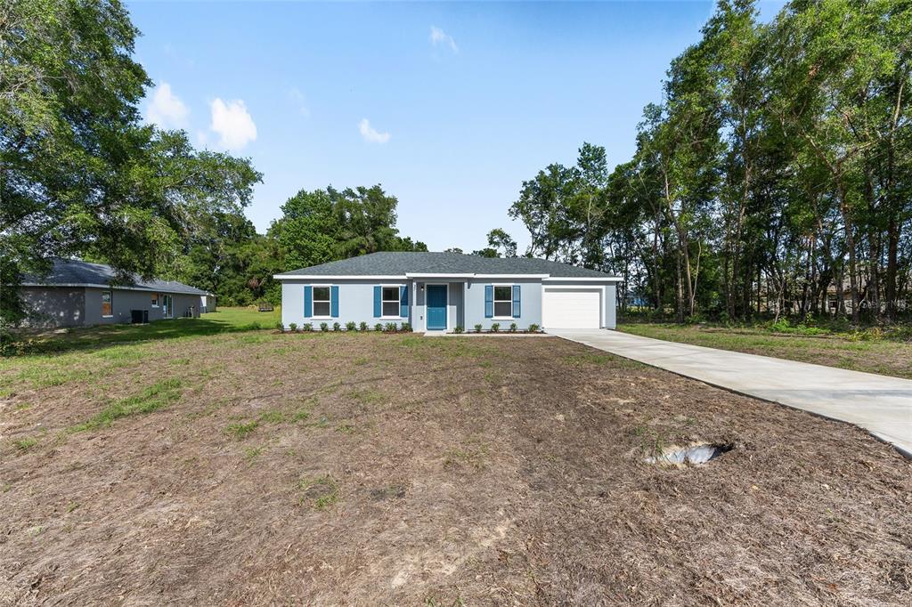 A single-story house with a blue door, gray shutters, and a concrete driveway — 37 DOGWOOD DRIVE PASS, OCALA, FL
