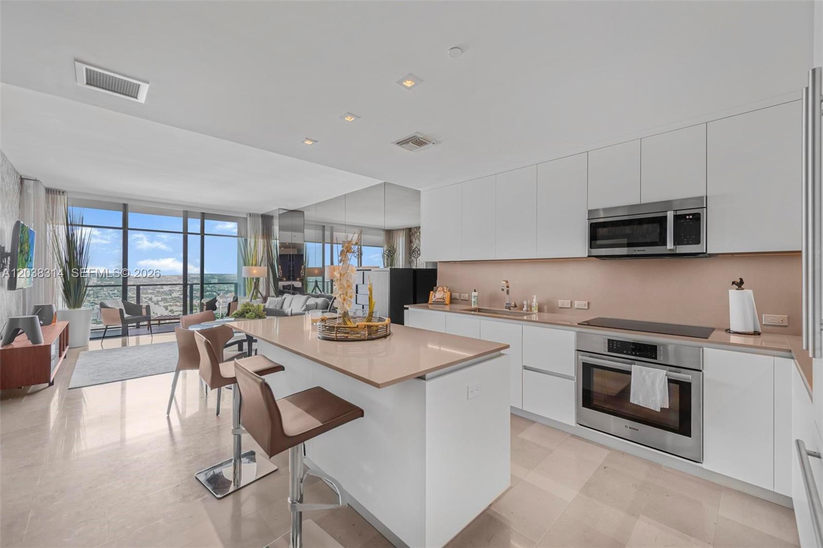 A modern kitchen with white cabinets and a center island overlooks a living area — 88 SW 7th St # 3806, Miami FL 33130, MIAMI, FL