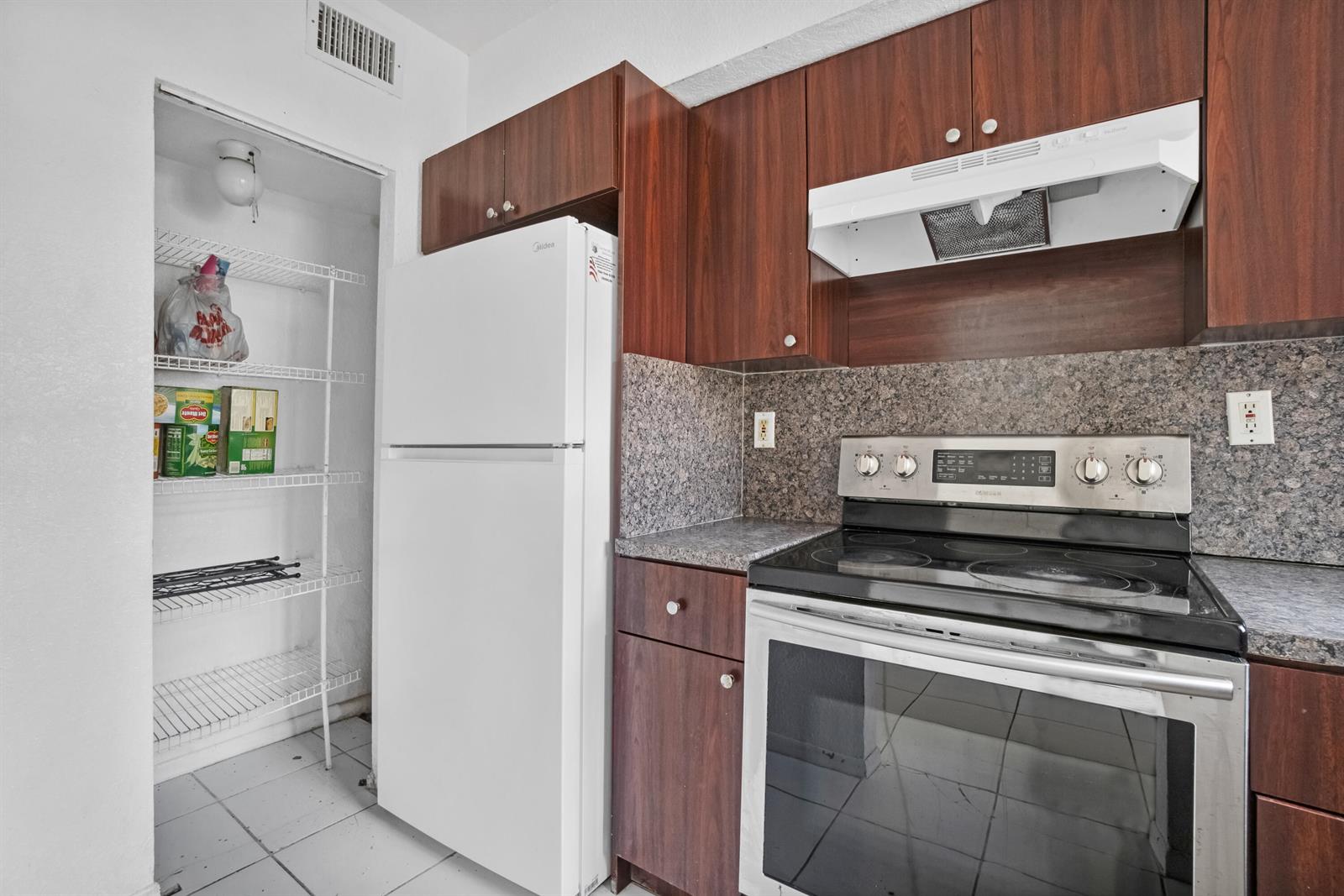 A kitchen features dark wood cabinets, a white refrigerator, a stainless steel stove, and pantry — 306 NW 84th Terrace # 306, Miami FL 33150, MIAMI, FL