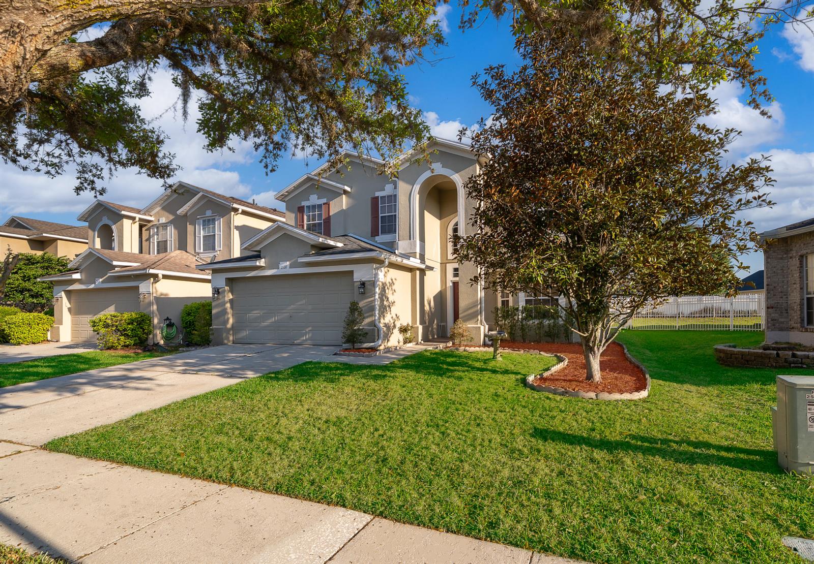 A two-story suburban house with a beige exterior, a two-car garage, and a front lawn — 2591 Dover Glen Circle, Orlando FL 32828, ORLANDO, FL