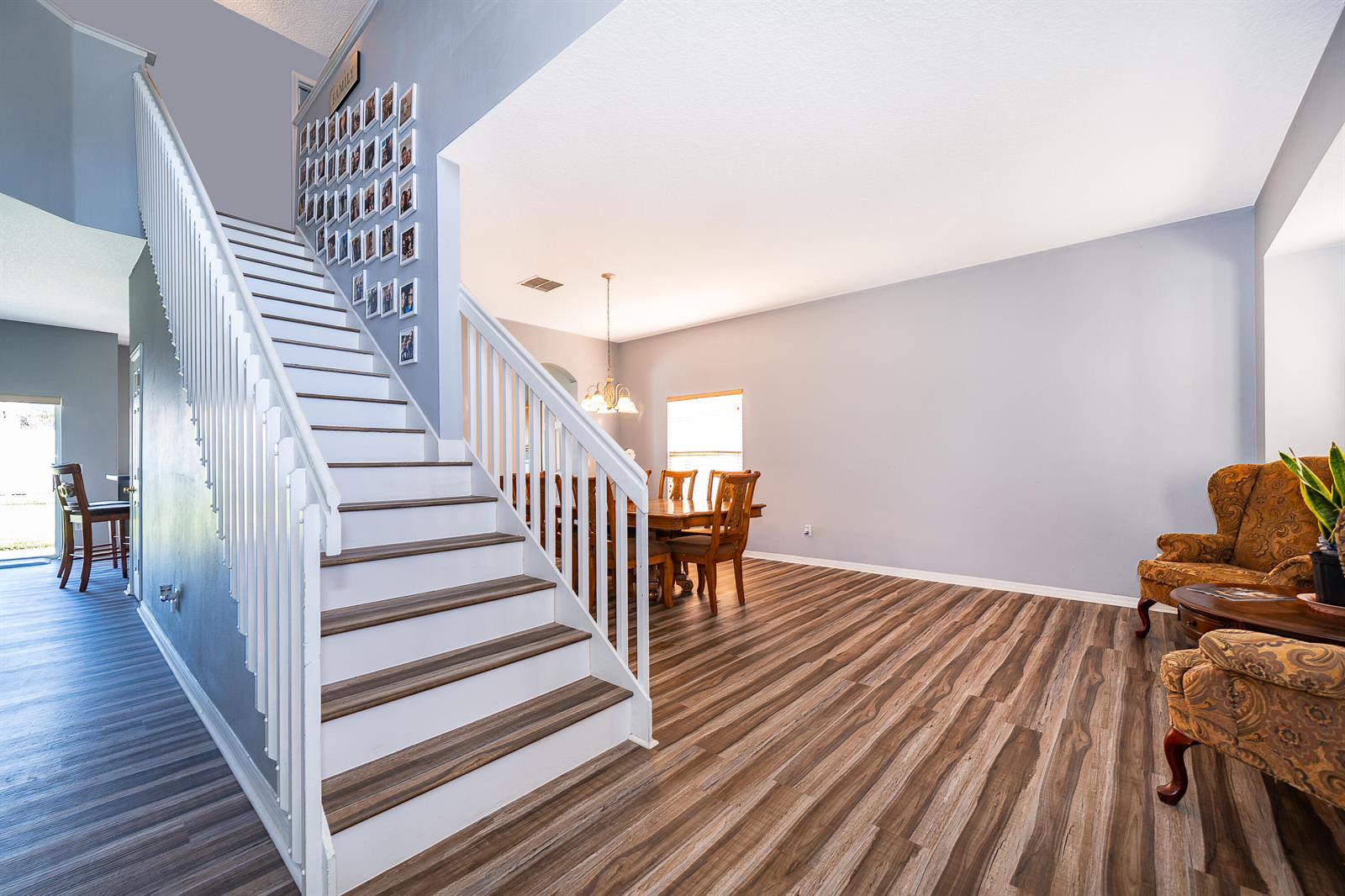 A staircase with wood treads and white railings leads to an open dining area — 2591 Dover Glen Circle, Orlando FL 32828, ORLANDO, FL
