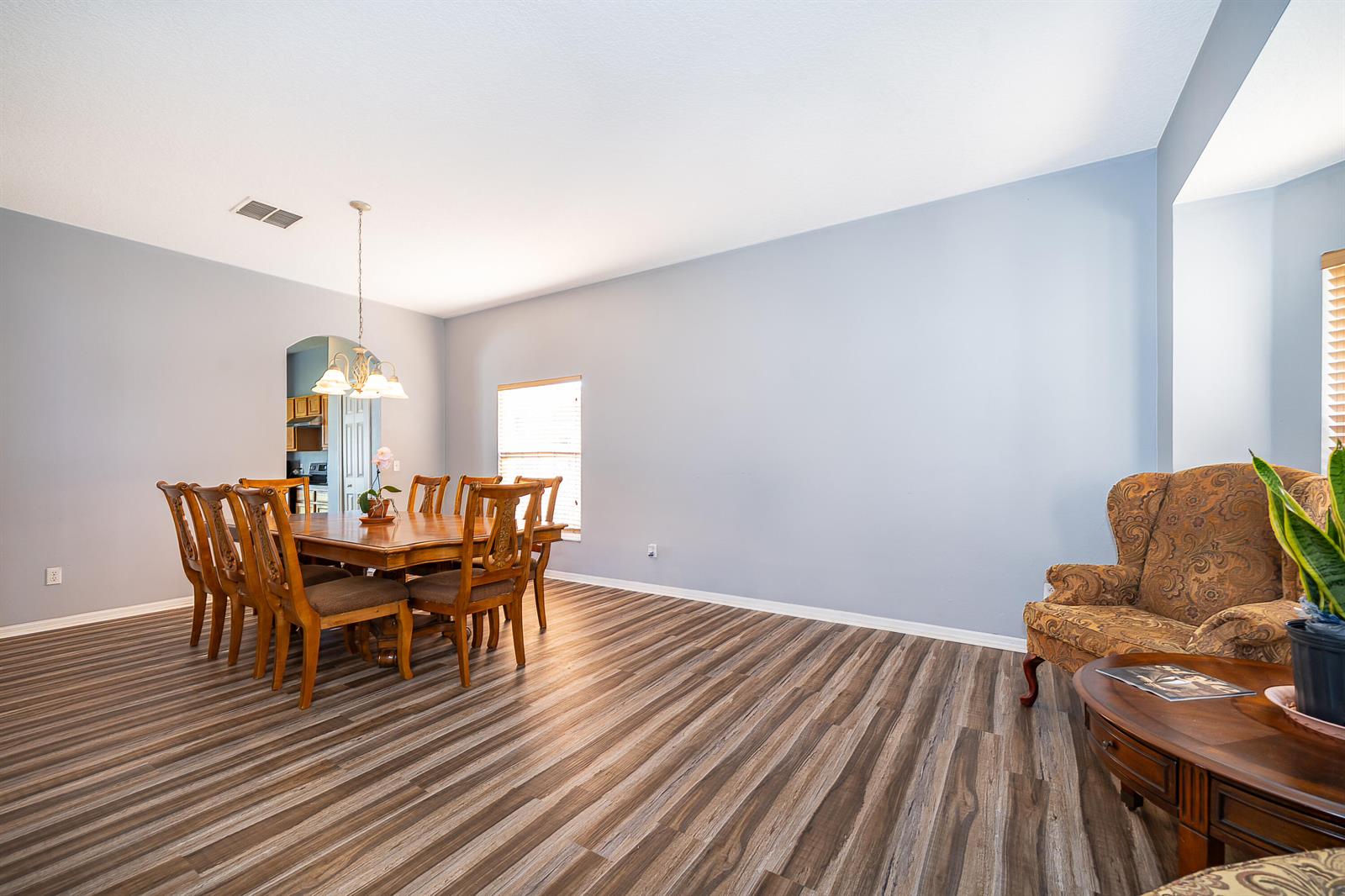 A dining area with wood-look flooring, a wooden table with chairs, and a patterned armchair — 2591 Dover Glen Circle, Orlando FL 32828, ORLANDO, FL