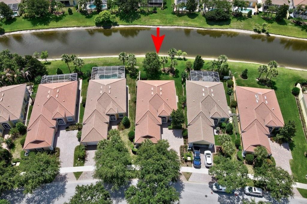 An aerial view shows a row of houses with tiled roofs bordering a narrow lake — VERO BEACH, FL