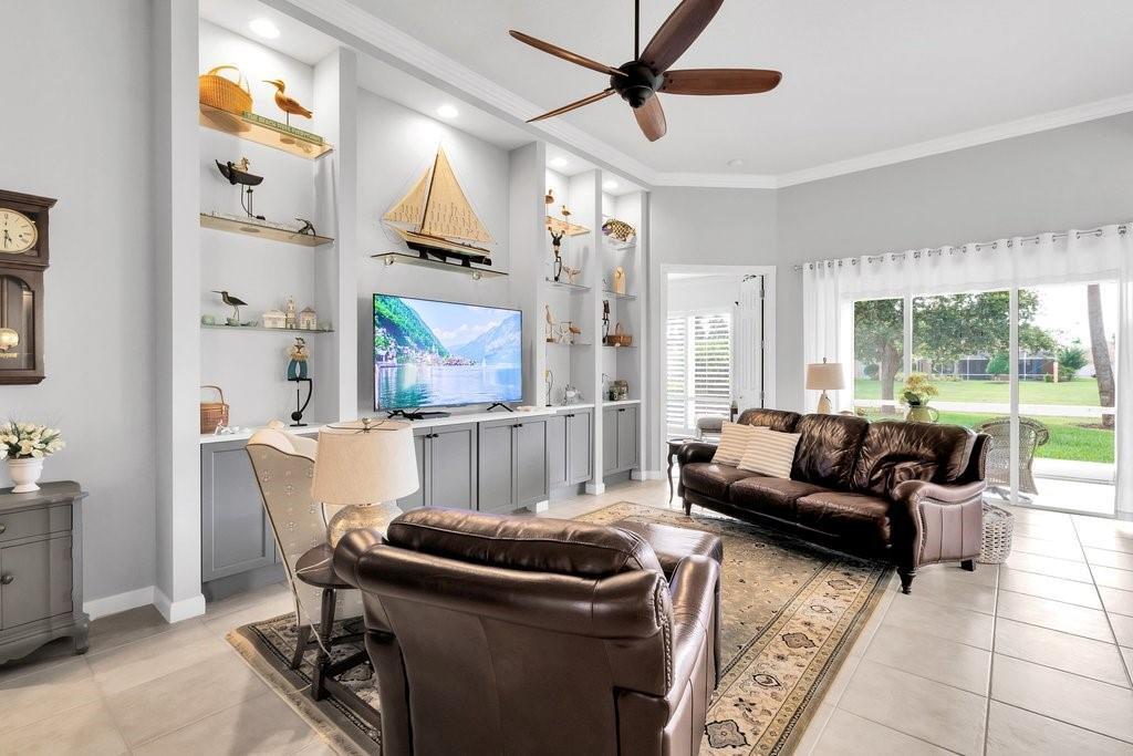 A living room with a built-in media center, leather furniture, and a large sliding glass door — VERO BEACH, FL