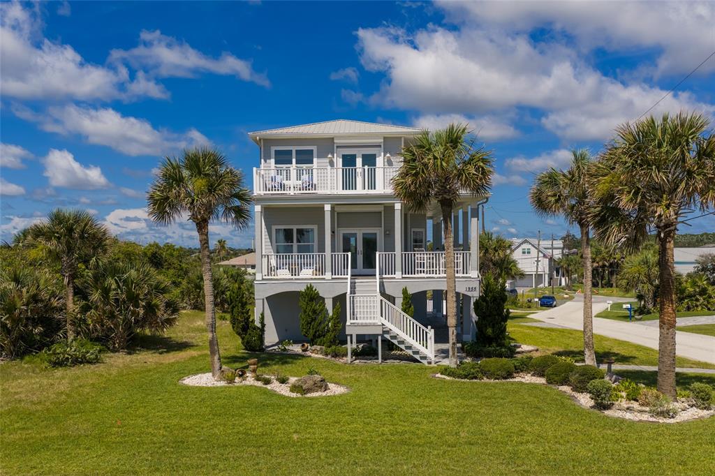 A three-story elevated house with two levels of balconies and palm trees in the yard — 1955 N CENTRAL AVENUE, FLAGLER BEACH, FL
