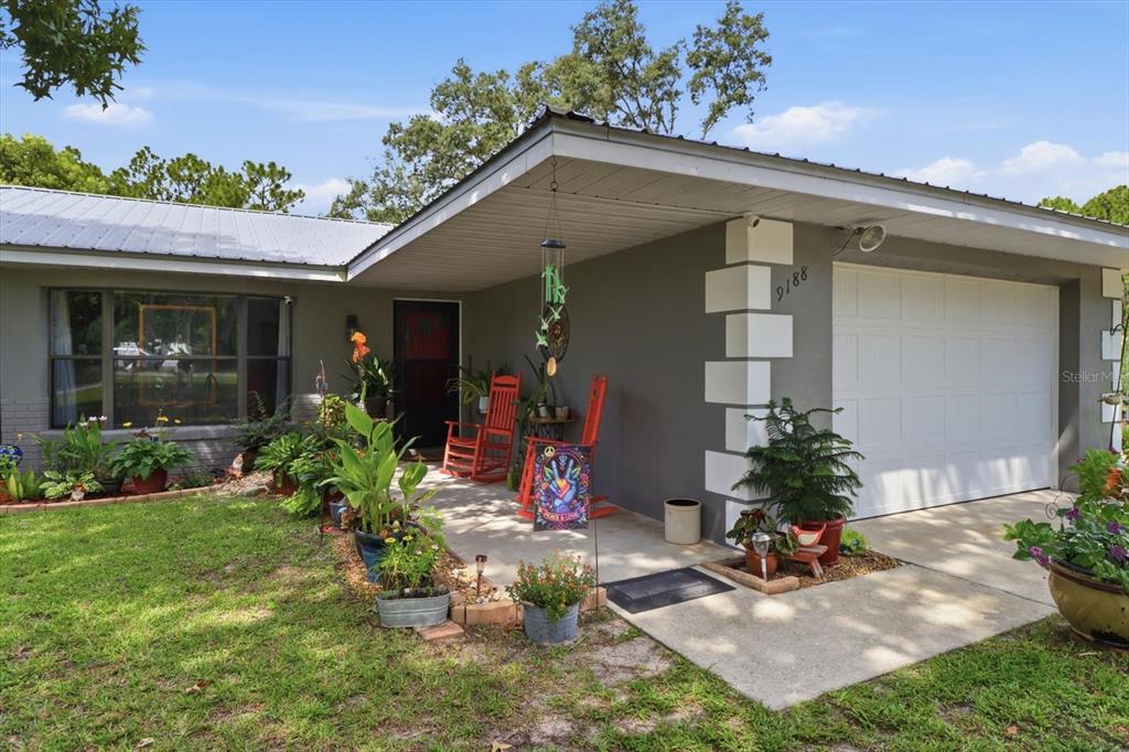 A gray house with a white garage door, a covered porch, and potted plants — 9188 N COMMODORE DRIVE, CITRUS SPRINGS, FL