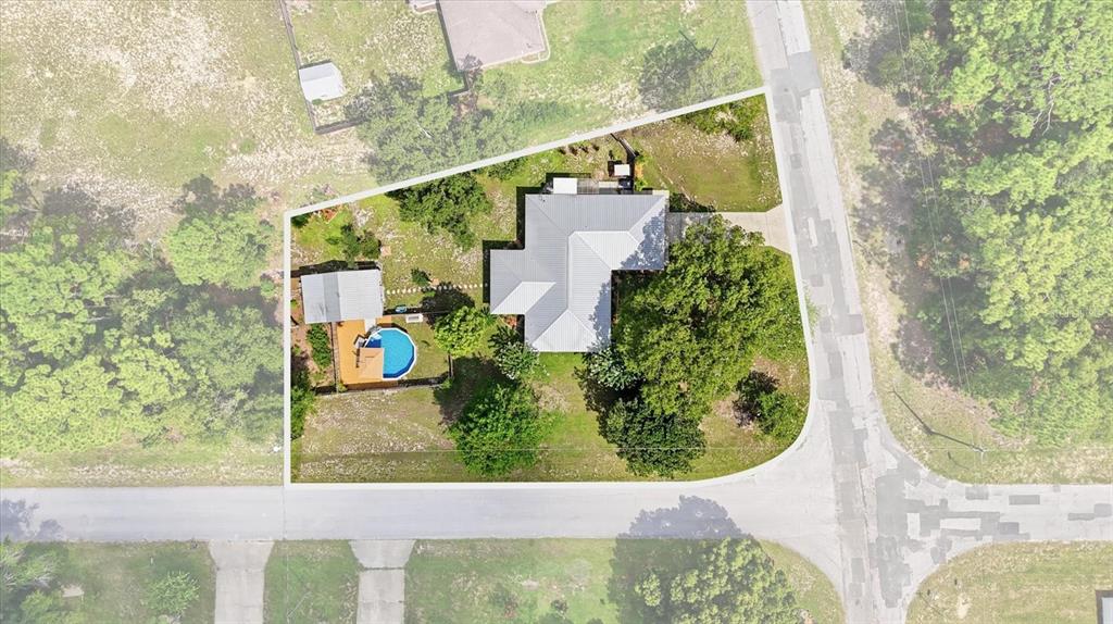 An aerial view shows a house with a metal roof, a pool, and a shed — 9188 N COMMODORE DRIVE, CITRUS SPRINGS, FL
