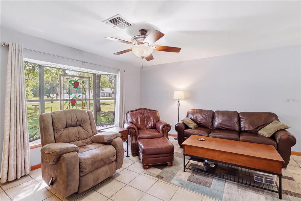 A living room features tile floors, a ceiling fan, a leather sofa, and a recliner — 9188 N COMMODORE DRIVE, CITRUS SPRINGS, FL