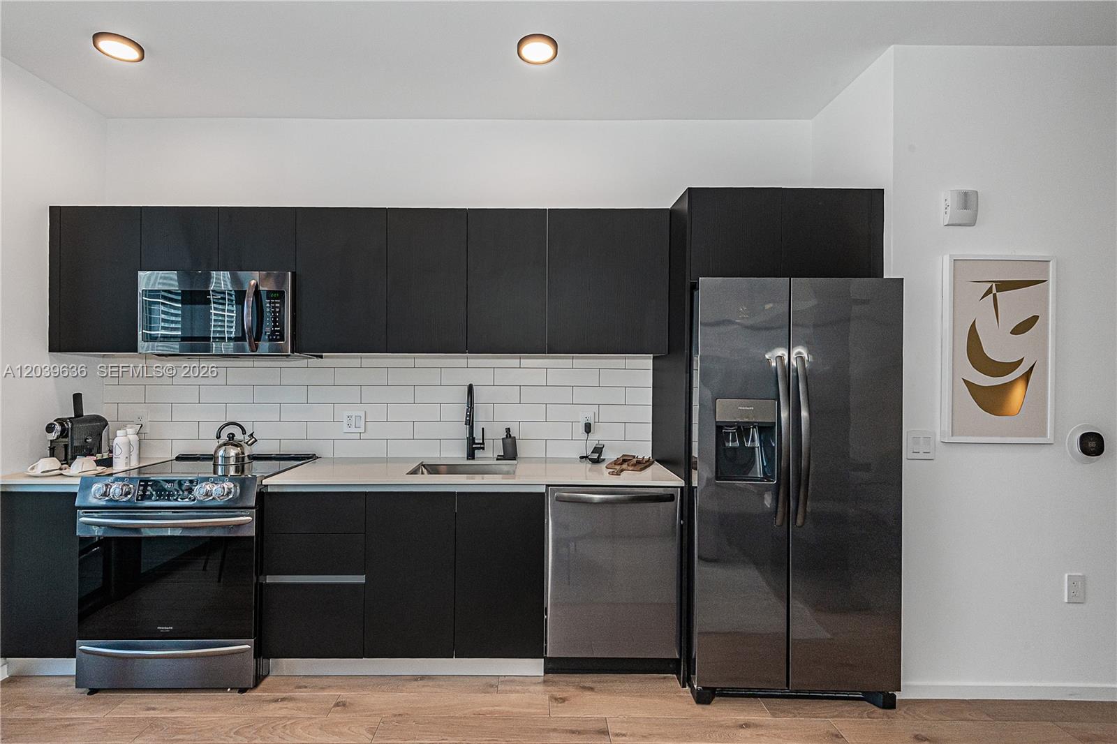 A modern kitchen features black cabinetry, stainless steel appliances, and a white subway tile backsplash — 398 NE 5th St # 2904, Miami FL 33132, MIAMI, FL