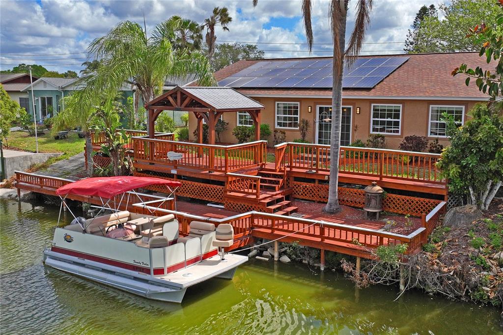 A waterfront house with a large wooden deck, gazebo, and a pontoon boat docked outside — 2529 SAN LUIS ROAD, HOLIDAY, FL