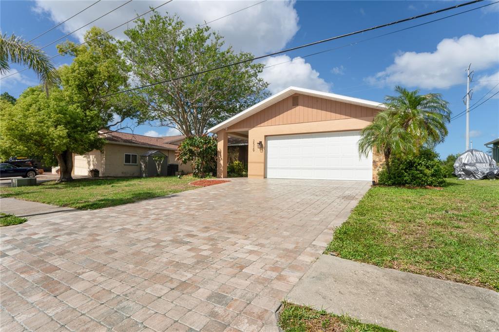A single-story house with a paved driveway, a two-car garage, and a palm tree — 2529 SAN LUIS ROAD, HOLIDAY, FL