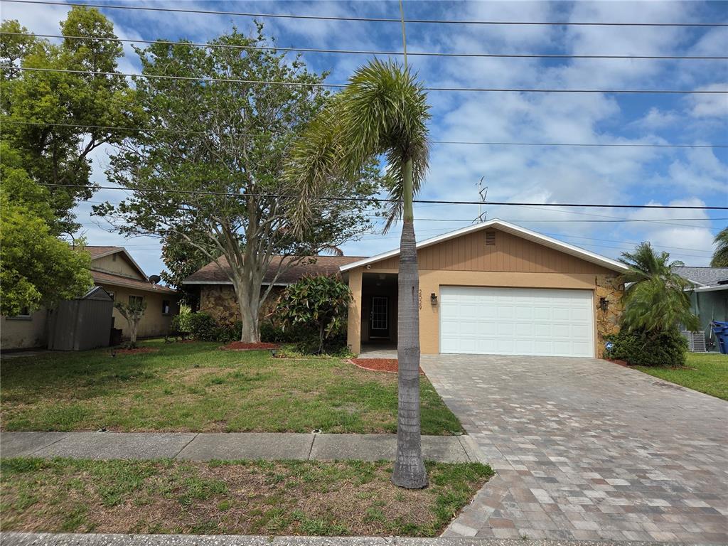 A single-story house with a stone facade, a paved driveway, and a palm tree out front — 2529 SAN LUIS ROAD, HOLIDAY, FL