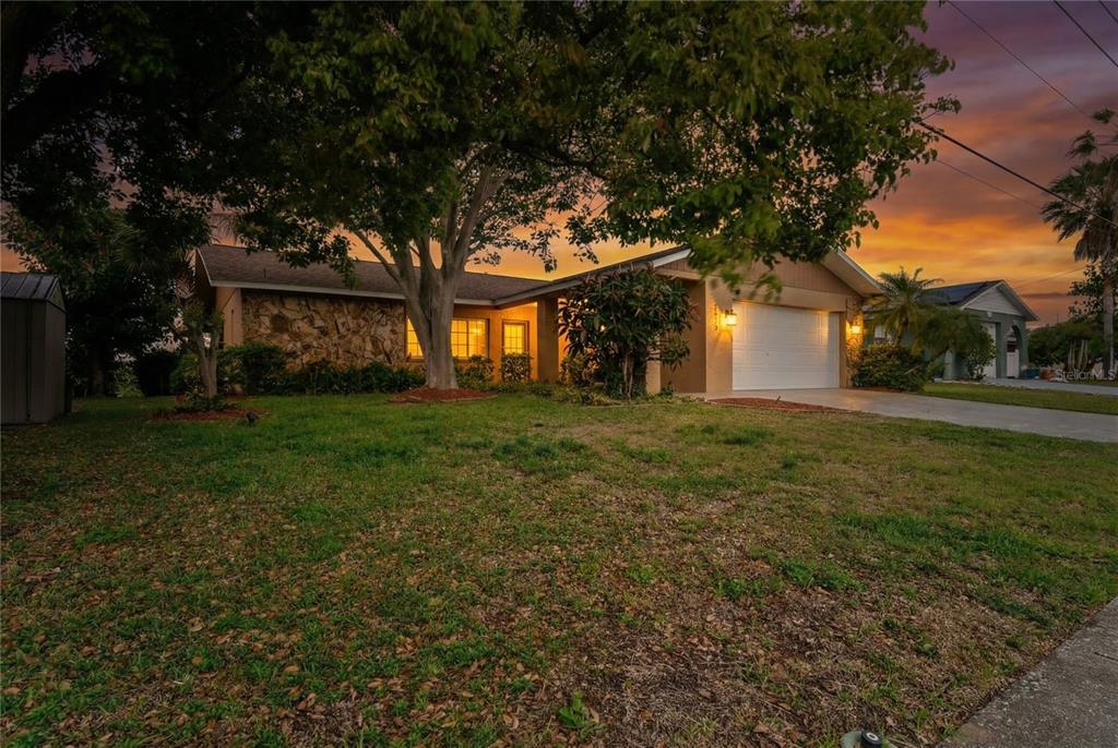 A single-story house with a stone facade, a two-car garage, and a large front tree — 2529 SAN LUIS ROAD, HOLIDAY, FL