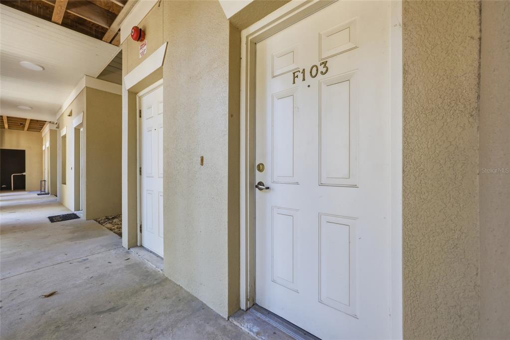 An exterior hallway shows a white door labeled F103 with a concrete walkway — 9172 SW 52ND ROAD UNIT 103, GAINESVILLE, FL