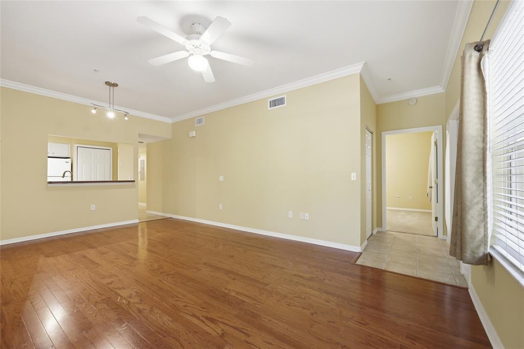 A living room with hardwood floors, yellow walls, a ceiling fan, and an adjacent kitchen — 9172 SW 52ND ROAD UNIT 103, GAINESVILLE, FL