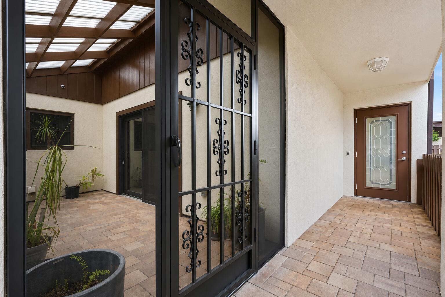 A covered patio with a decorative metal security door and a brown front entry door — 6774 Wheaton Lane, Lake Worth FL 33467, LAKE WORTH, FL