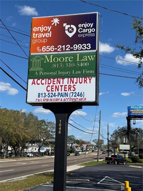 A tall, multi-tenant business sign stands along a road under a blue sky — 1046 W BUSCH BOULEVARD UNIT 100, TAMPA, FL