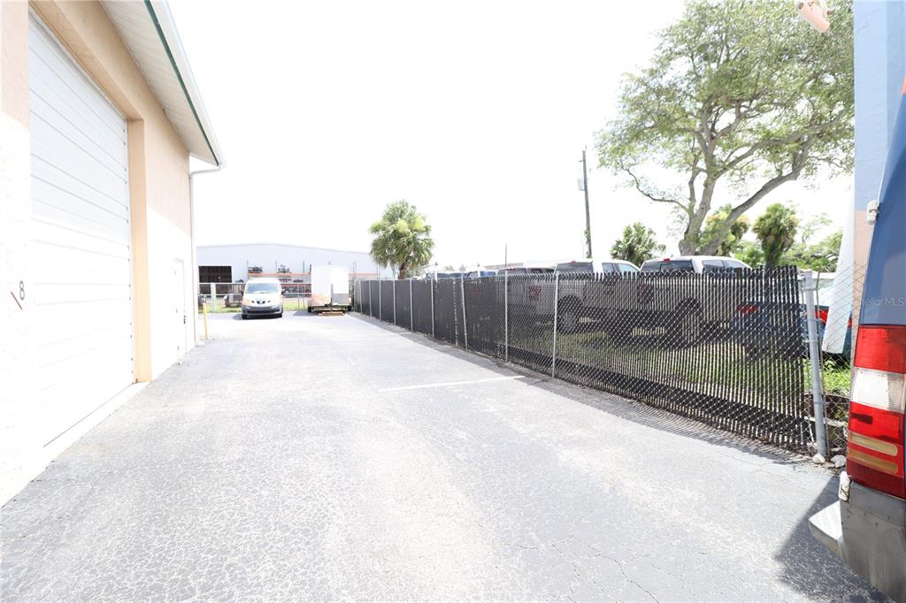 An outdoor paved area sits between a building wall and a chain-link fence — 1158  # 8 MARKET CIRCLE UNIT 8, PORT CHARLOTTE, FL