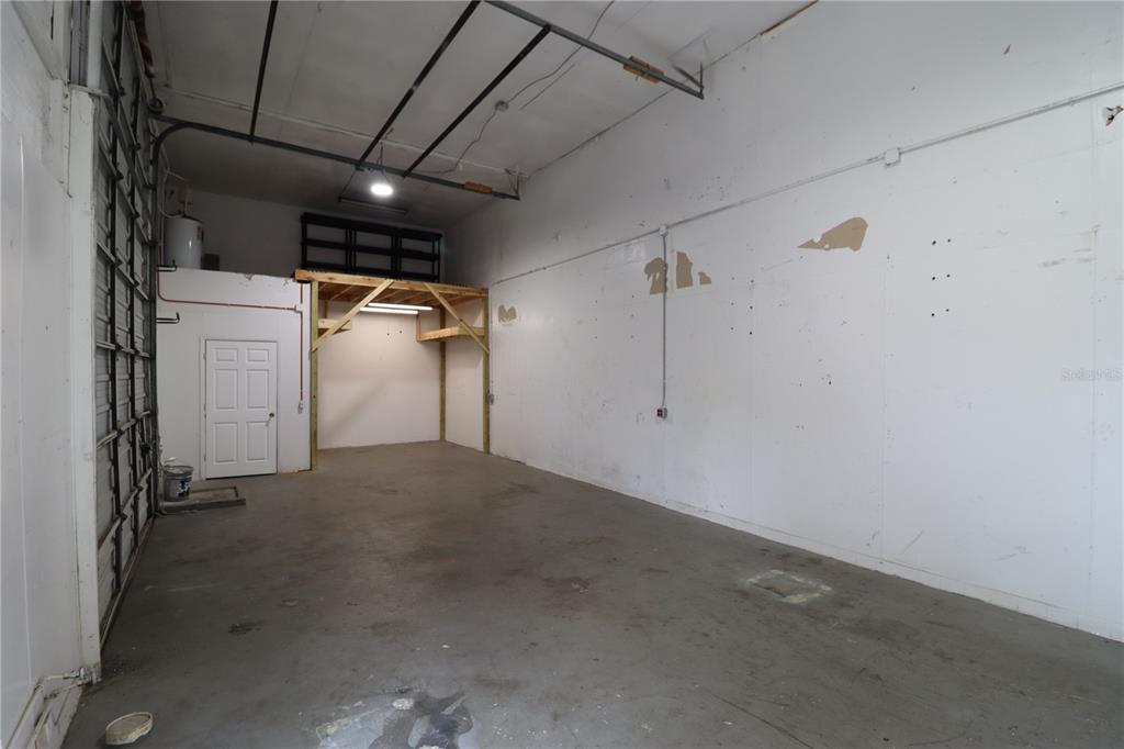 An empty industrial storage unit features a concrete floor, white walls, and a wooden loft — 1158  # 8 MARKET CIRCLE UNIT 8, PORT CHARLOTTE, FL