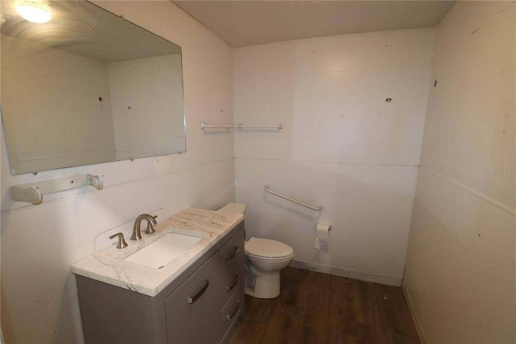 A bathroom features a gray vanity with a marble countertop, a mirror, and a toilet — 1158  # 8 MARKET CIRCLE UNIT 8, PORT CHARLOTTE, FL