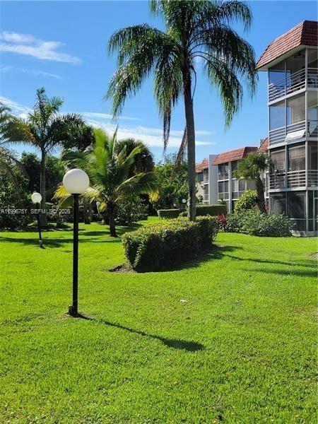 A grassy lawn features palm trees, a lamp post, and a multi-story residential building — 3774 Inverrary Blvd # 206P, Lauderhill FL 33319, LAUDERHILL, FL