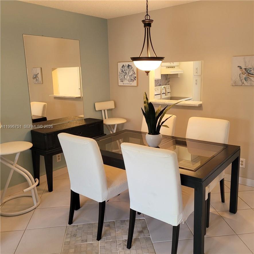 A dining area features a glass-top table, white chairs, a pendant light, and a mirror — 3774 Inverrary Blvd # 206P, Lauderhill FL 33319, LAUDERHILL, FL