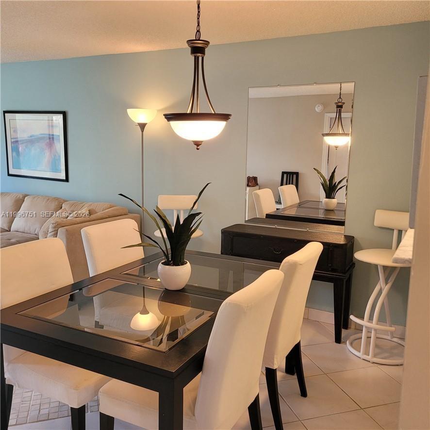 A dining area features a glass-topped table, white chairs, a pendant light, and a mirror — 3774 Inverrary Blvd # 206P, Lauderhill FL 33319, LAUDERHILL, FL