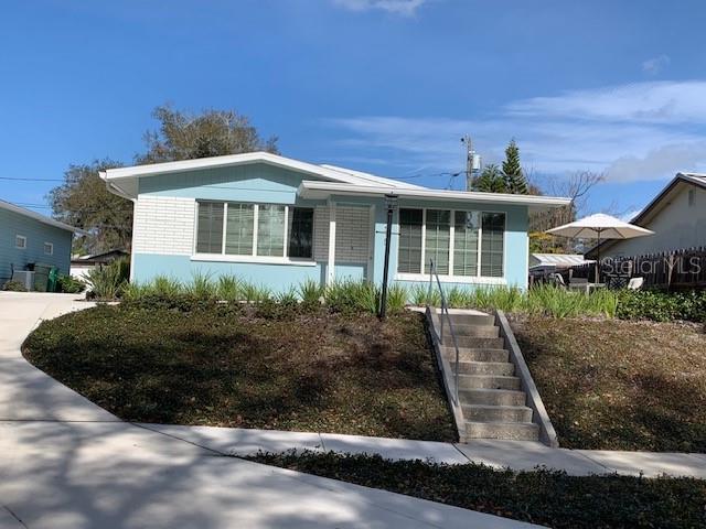 A light blue single-story house with a white roof and concrete steps leading to the entrance — 1275 WOODDELL DRIVE, SAFETY HARBOR, FL