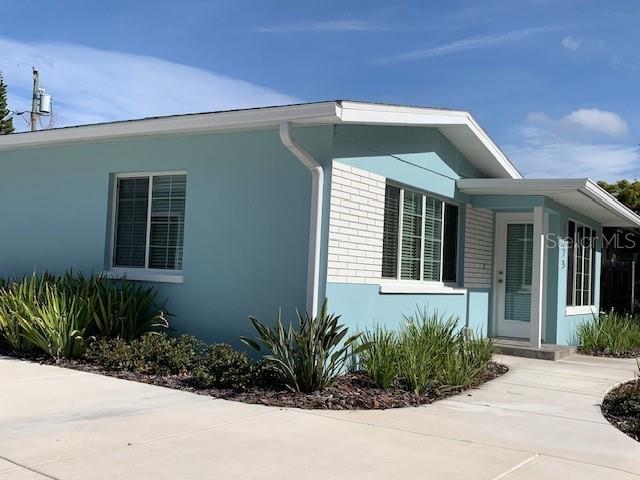 A light blue house with white brick accents and a concrete walkway under a blue sky — 1275 WOODDELL DRIVE, SAFETY HARBOR, FL