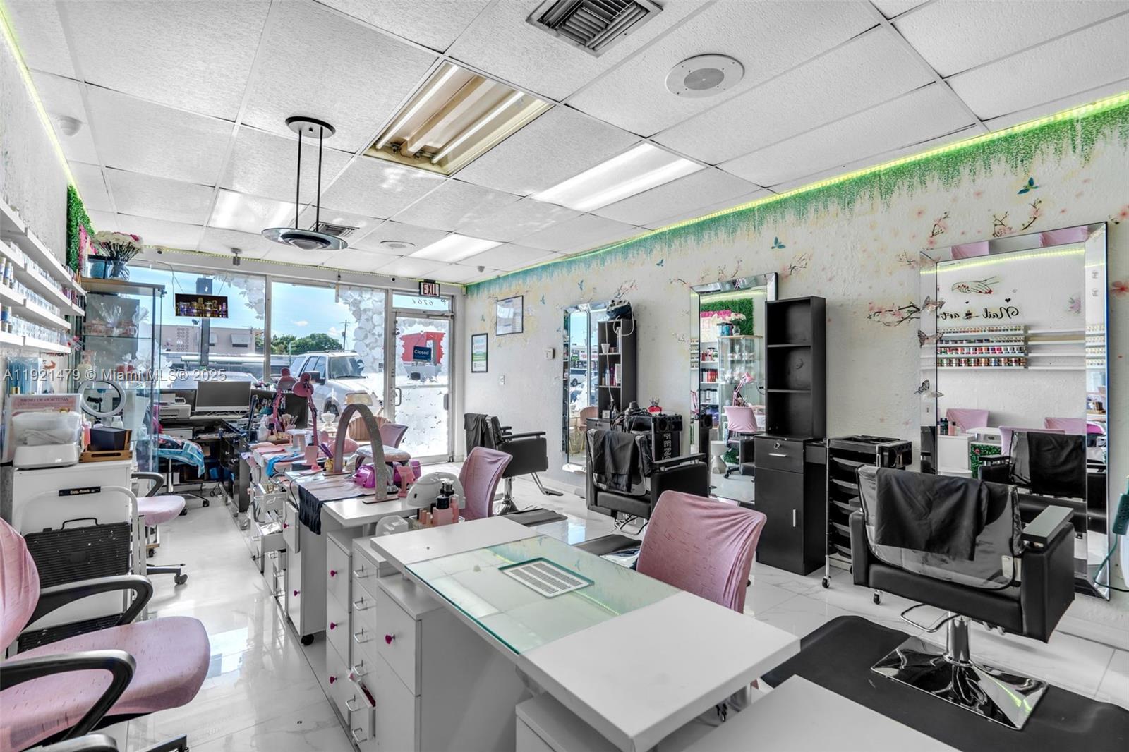 A bright nail salon features multiple workstations, pink chairs, wall mirrors, and decorative floral wallpaper — 6761 W Flagler St, Miami FL 33144, MIAMI, FL