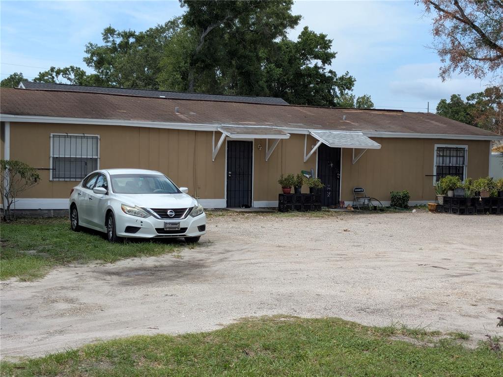 A single-story tan house with two front doors and a gravel driveway — 3014 N 48TH STREET, TAMPA, FL