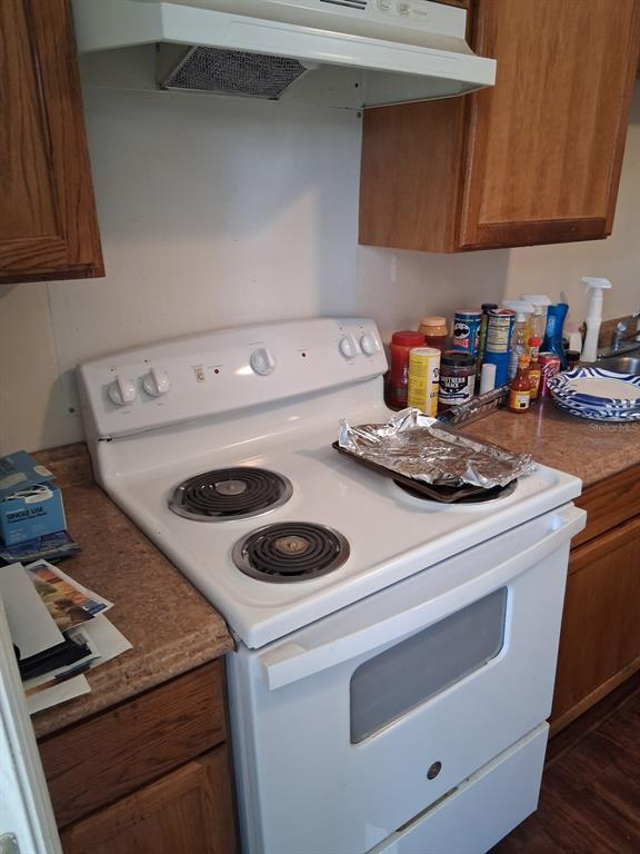 A white electric stove sits between wooden cabinets in a kitchen with laminate countertops — 3014 N 48TH STREET, TAMPA, FL