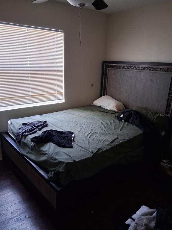 A bedroom features a bed with a dark wood frame and a window with blinds — 3014 N 48TH STREET, TAMPA, FL
