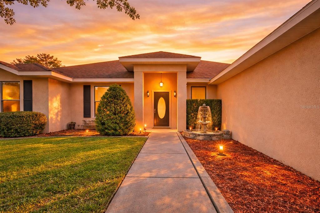 A single-story house exterior features a concrete walkway, a front door, and a stone fountain — 11318 SUMMER WIND COURT, CLERMONT, FL