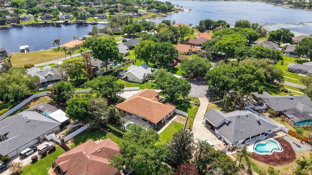An aerial view shows several suburban houses with swimming pools near a lake — 11318 SUMMER WIND COURT, CLERMONT, FL