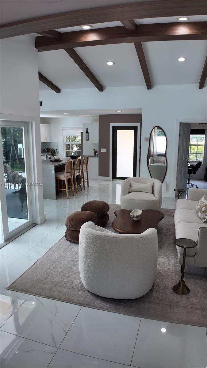 A living room with white tile floors, exposed ceiling beams, and a neutral-toned seating area — 14605 SW 142nd Pl, Miami FL 33186, MIAMI, FL