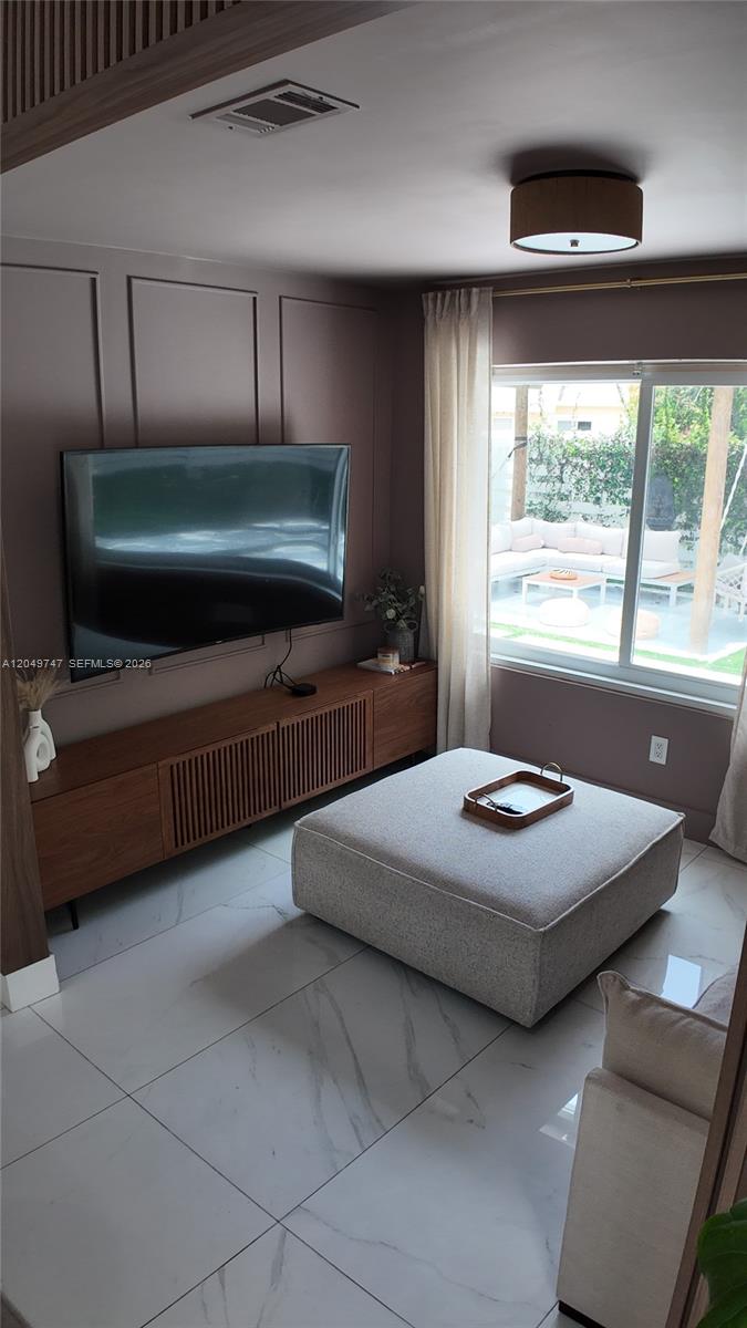 A living room features a wall-mounted television, a wooden media console, and a large ottoman — 14605 SW 142nd Pl, Miami FL 33186, MIAMI, FL