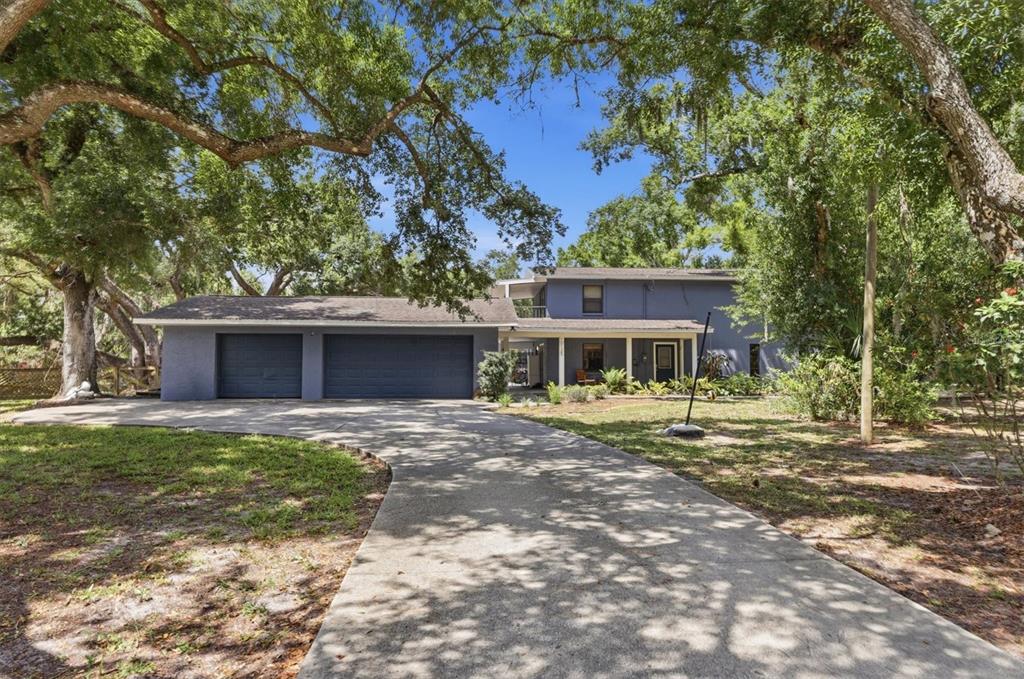 A two-story blue house with a three-car garage and a long concrete driveway — 10125 OAK RUN DRIVE, BRADENTON, FL