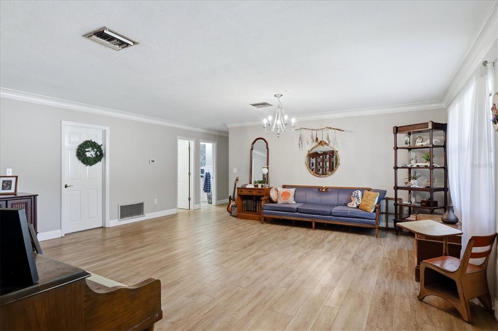 A living room features light wood-look flooring, a blue sofa, and a white chandelier — 10125 OAK RUN DRIVE, BRADENTON, FL