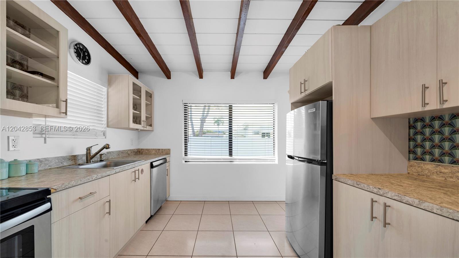 A kitchen features light wood cabinets, a stainless steel refrigerator, and exposed ceiling beams — 1704 Rodman St # 3, Hollywood FL 33020, HOLLYWOOD, FL