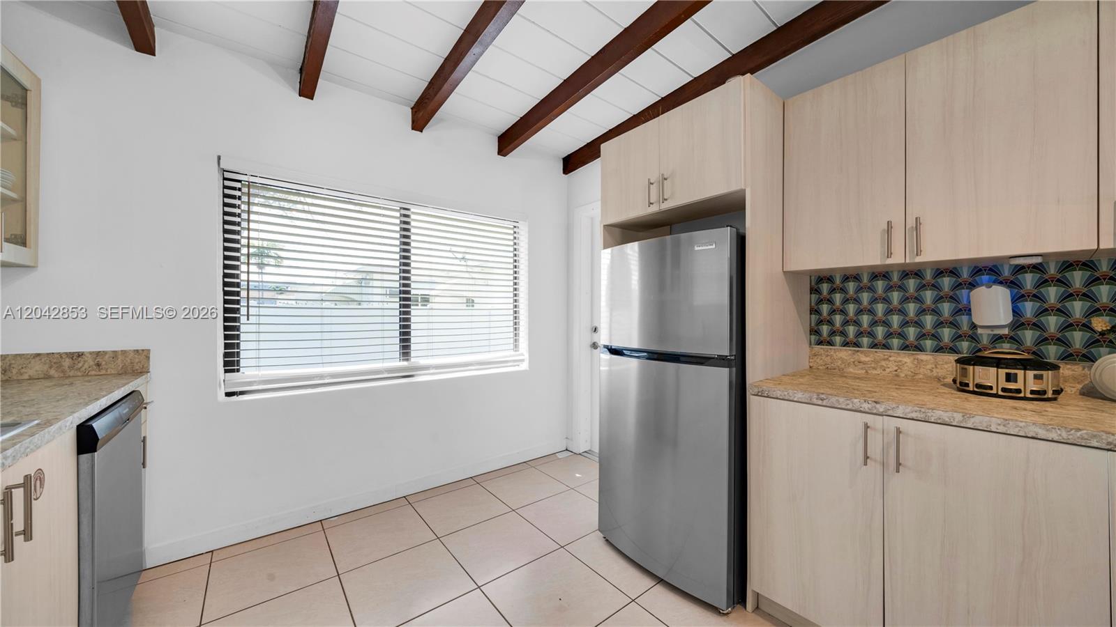 A kitchen features light wood cabinets, a stainless steel refrigerator, and a patterned tile backsplash — 1704 Rodman St # 3, Hollywood FL 33020, HOLLYWOOD, FL