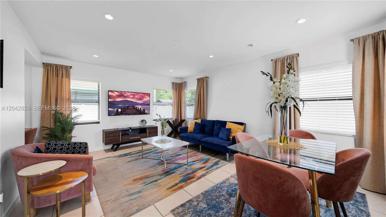 A living and dining area features a blue sofa, pink chairs, and a glass table — 1704 Rodman St # 3, Hollywood FL 33020, HOLLYWOOD, FL