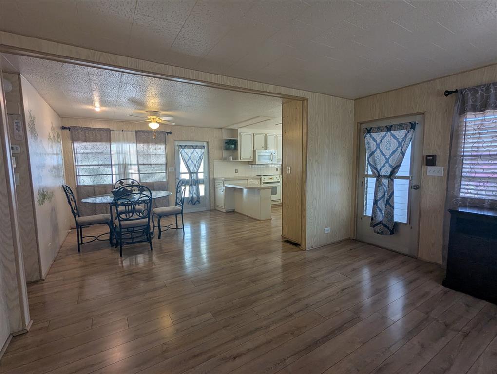 A dining area and kitchen feature wood-look flooring, wood paneling, and a glass-topped table — 6 PINE LANE, HAINES CITY, FL