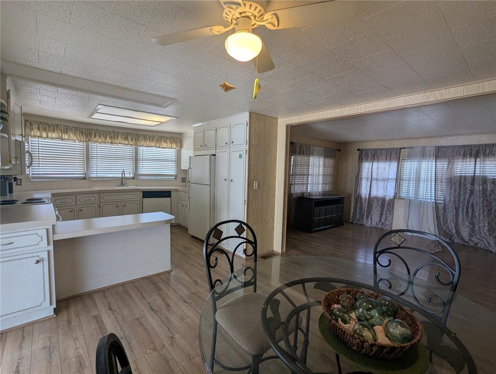 A kitchen with white cabinets and a dining area with a glass table — 6 PINE LANE, HAINES CITY, FL