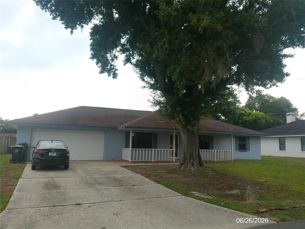 A single-story house with a light blue exterior, a two-car garage, and a large tree — 1601 ARCHERS PATH, LAKELAND, FL